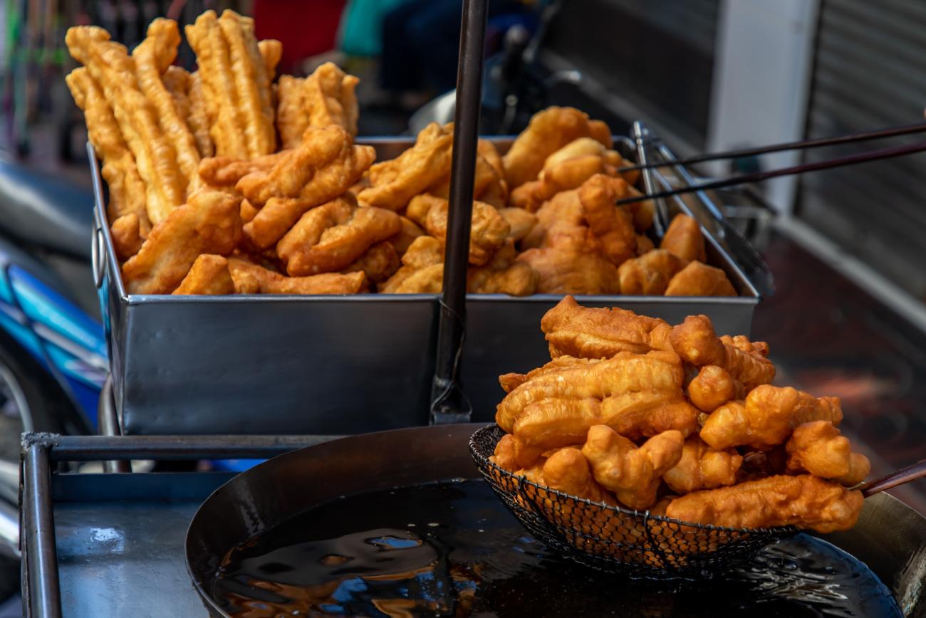 Fried dough strips taken out of a wok of oil at a Chinese streed market